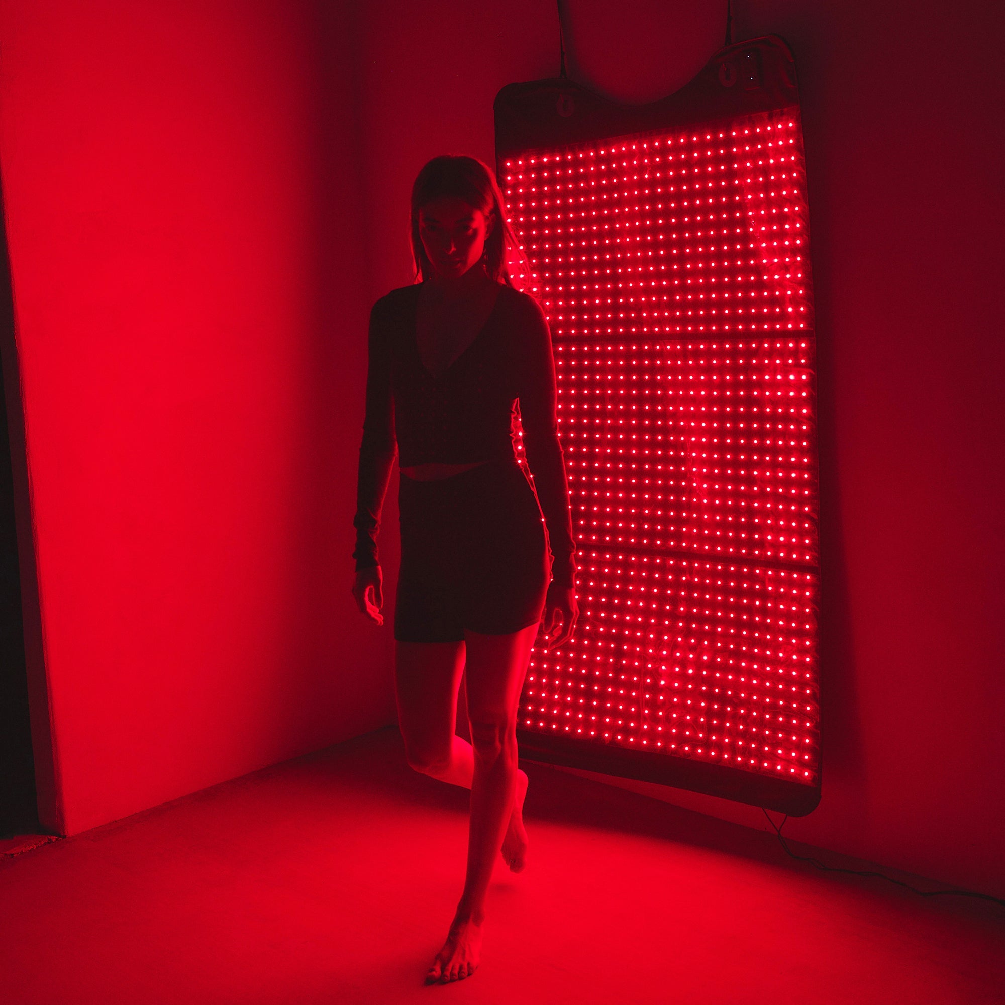 Person standing in front of and on Full Body Red Light Mat